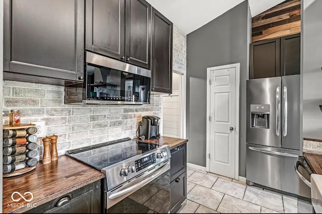 kitchen with dark brown cabinetry, butcher block countertops, light tile patterned floors, stainless steel appliances, and decorative backsplash