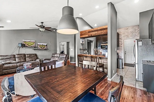 dining room with ceiling fan, high vaulted ceiling, and light wood-type flooring