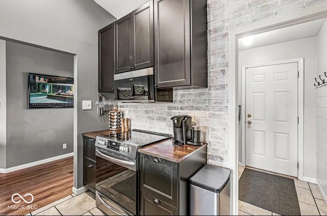 kitchen with electric stove, light tile patterned floors, decorative backsplash, and dark brown cabinets