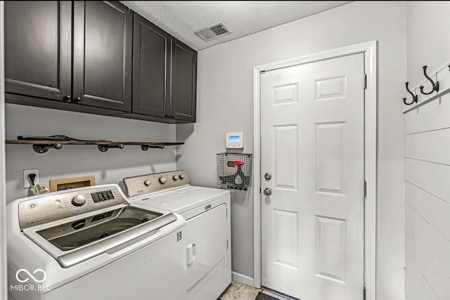 laundry room with cabinets, washer and dryer, and a textured ceiling