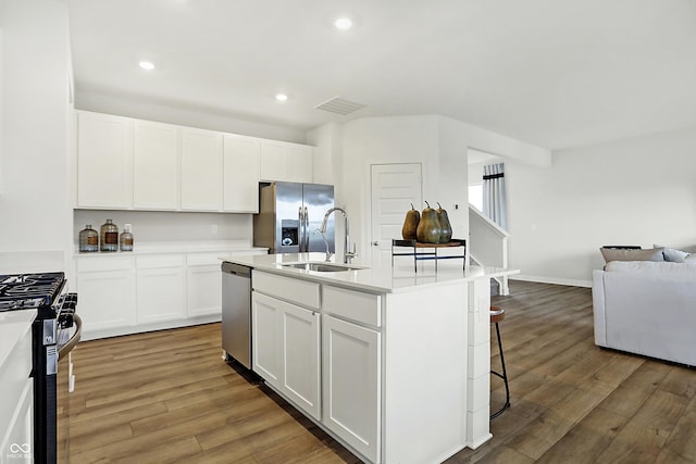 kitchen featuring sink, a breakfast bar area, appliances with stainless steel finishes, white cabinetry, and an island with sink