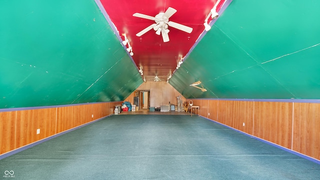 bonus room featuring ceiling fan, lofted ceiling, wooden walls, and carpet