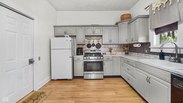 kitchen featuring sink, gray cabinets, black dishwasher, white refrigerator, and stainless steel range with gas cooktop