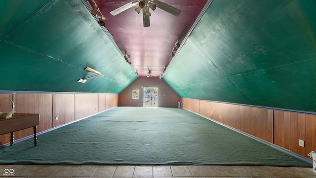 additional living space with lofted ceiling, light carpet, and wooden walls