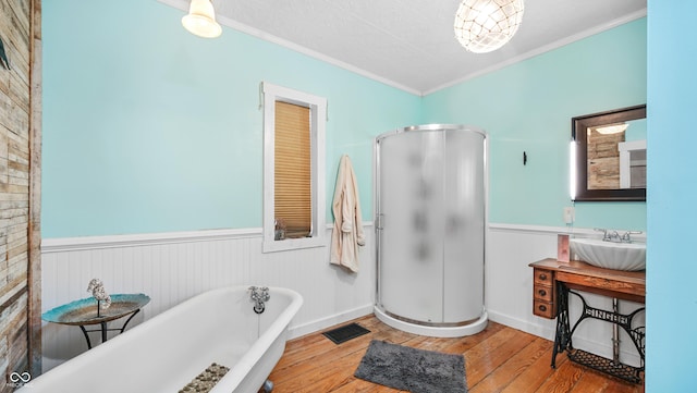 bathroom featuring ornamental molding, wood-type flooring, shower with separate bathtub, and sink