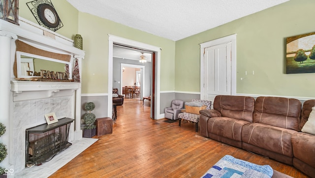 living room with hardwood / wood-style floors, a tile fireplace, and a textured ceiling