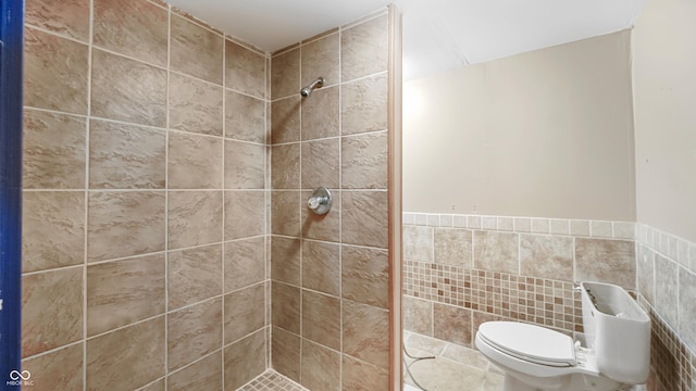 bathroom featuring tile walls, toilet, and tiled shower