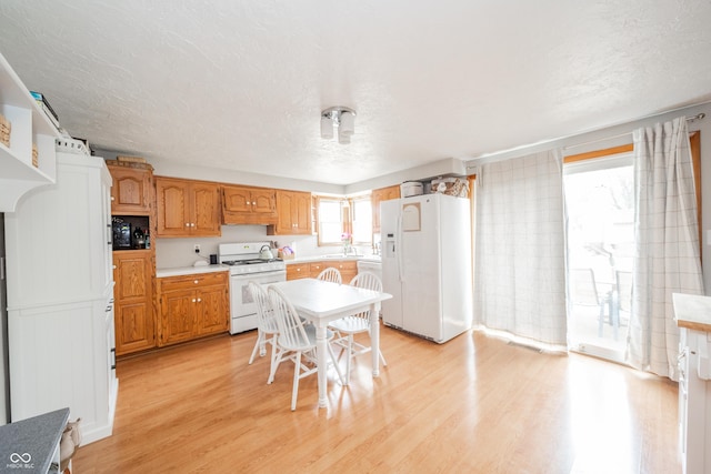 kitchen with sink, white appliances, light hardwood / wood-style floors, and a textured ceiling