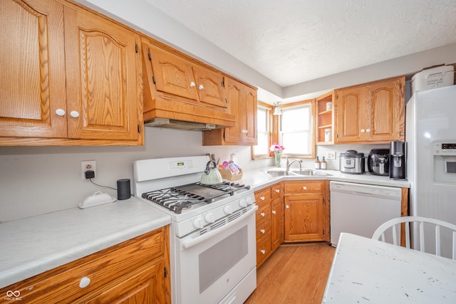 kitchen with sink, custom exhaust hood, a textured ceiling, light wood-type flooring, and white appliances