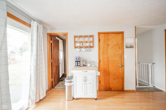 hall with light hardwood / wood-style floors and a textured ceiling