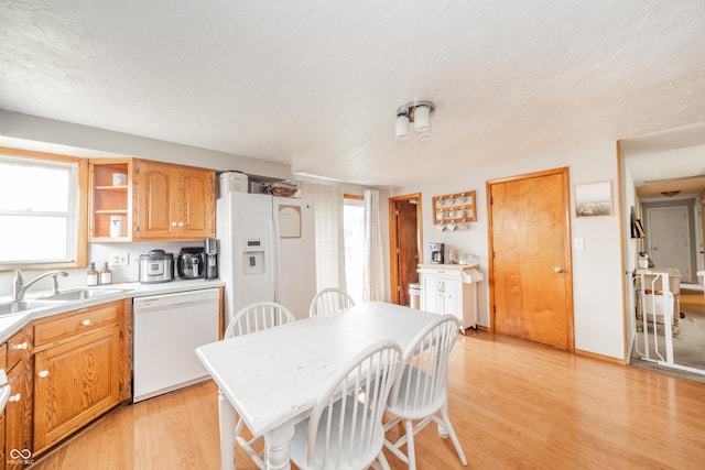 kitchen featuring white dishwasher, sink, light hardwood / wood-style floors, and a textured ceiling