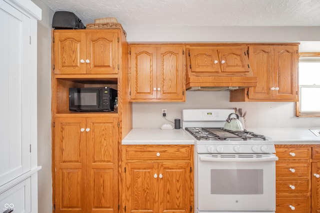 kitchen featuring custom exhaust hood, a textured ceiling, and gas range gas stove