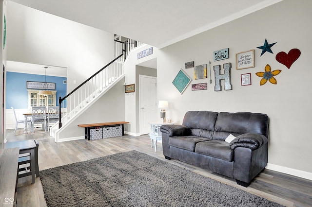 living room with crown molding, wood-type flooring, and a high ceiling