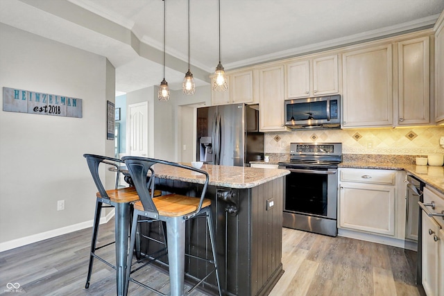 kitchen with a kitchen bar, decorative light fixtures, a kitchen island, stainless steel appliances, and light stone countertops