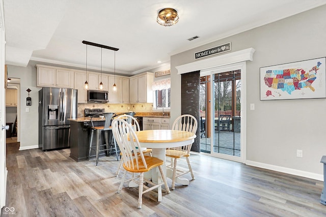 dining room with crown molding, sink, and light wood-type flooring