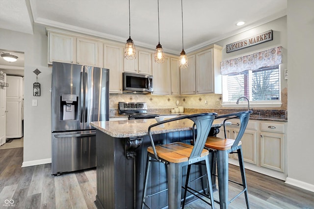 kitchen featuring stainless steel appliances, cream cabinets, decorative light fixtures, and dark stone counters