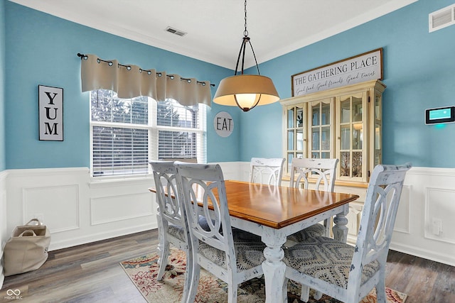 dining area with crown molding and dark wood-type flooring