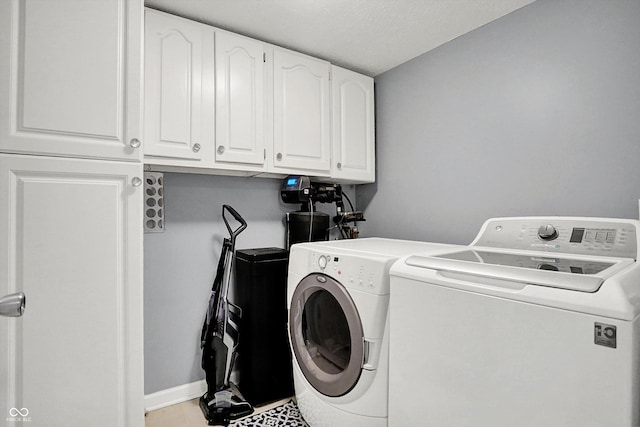 clothes washing area featuring cabinets and washing machine and clothes dryer