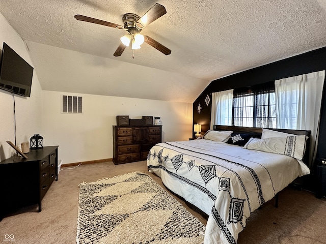 bedroom featuring ceiling fan, vaulted ceiling, light colored carpet, and a textured ceiling