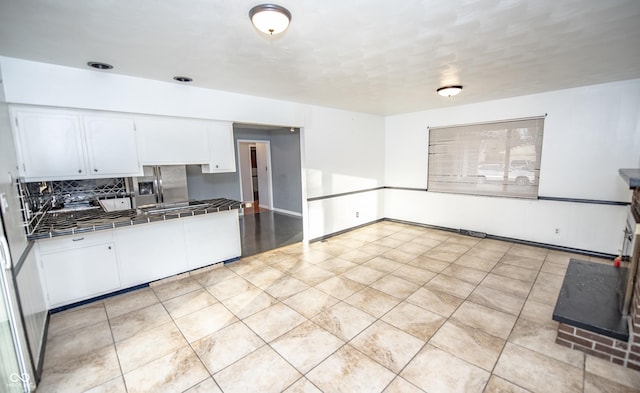 kitchen with tasteful backsplash, light tile patterned flooring, tile countertops, and white cabinets