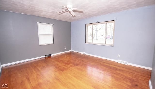 unfurnished room with ceiling fan, hardwood / wood-style flooring, and a textured ceiling