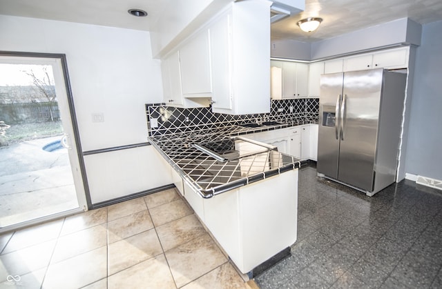 kitchen with white cabinetry, stainless steel fridge, and decorative backsplash