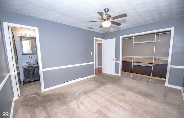 unfurnished bedroom with sink, carpet, ceiling fan, ensuite bath, and a closet