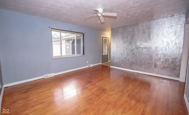 unfurnished room with dark hardwood / wood-style floors, a textured ceiling, and ceiling fan