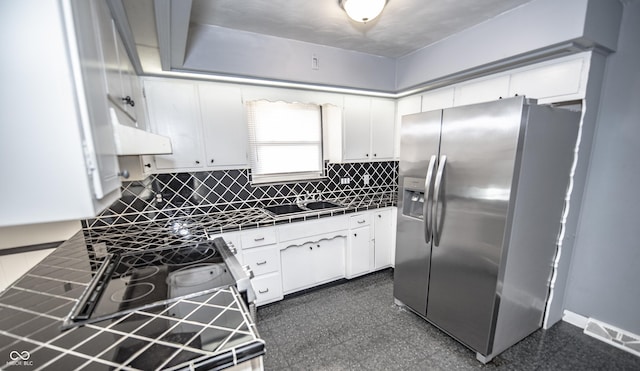 kitchen with appliances with stainless steel finishes, tile counters, white cabinets, and decorative backsplash