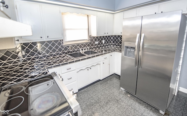 kitchen with white cabinetry, sink, stainless steel fridge, and backsplash