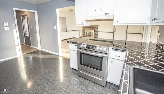 kitchen featuring stainless steel electric stove, tile counters, and white cabinets