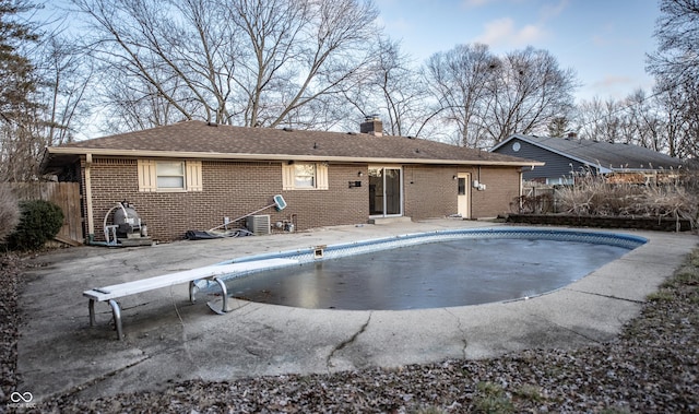 rear view of property featuring a patio area and a covered pool