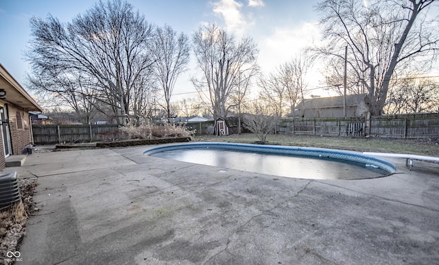 pool at dusk with a diving board and a patio area