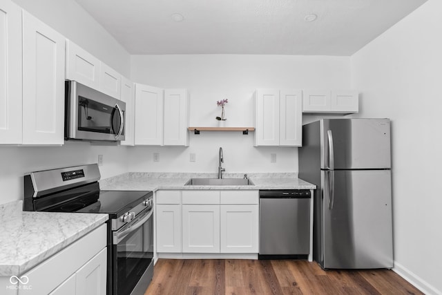 kitchen with sink, white cabinetry, stainless steel appliances, dark hardwood / wood-style floors, and light stone countertops