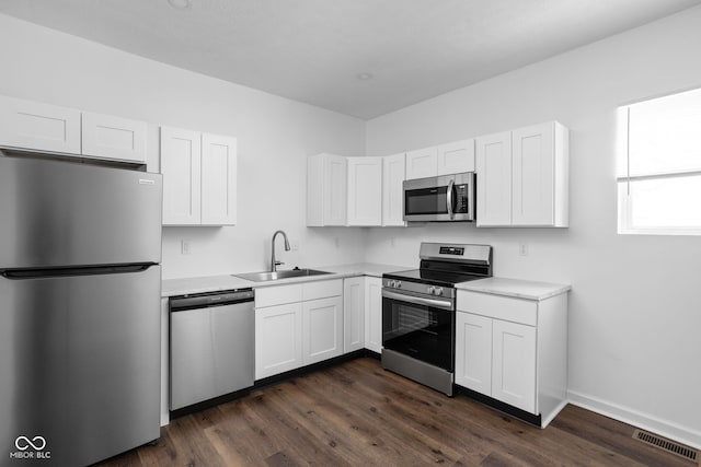 kitchen with stainless steel appliances, white cabinetry, sink, and dark hardwood / wood-style floors