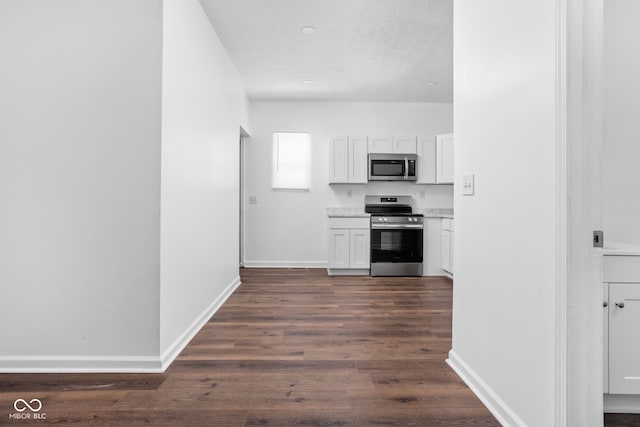 kitchen featuring dark wood-type flooring, stainless steel appliances, and white cabinets