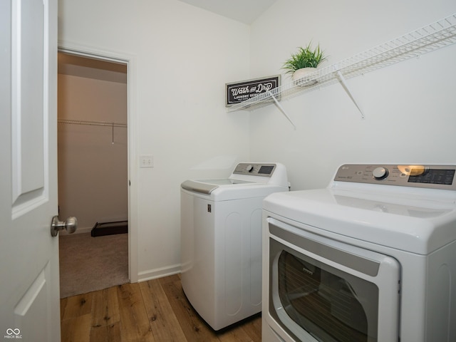 washroom featuring laundry area, baseboards, washer and clothes dryer, and light wood-style floors