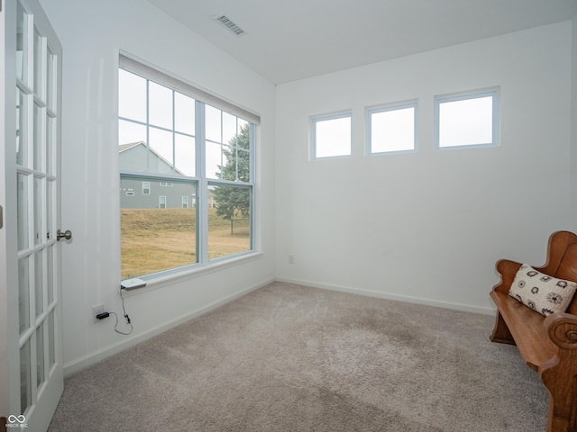 empty room featuring carpet floors, visible vents, and baseboards