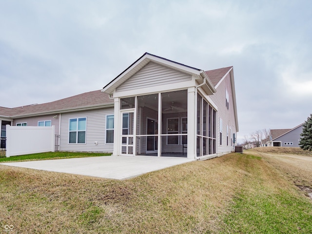 rear view of house featuring a sunroom, a patio area, fence, and a lawn