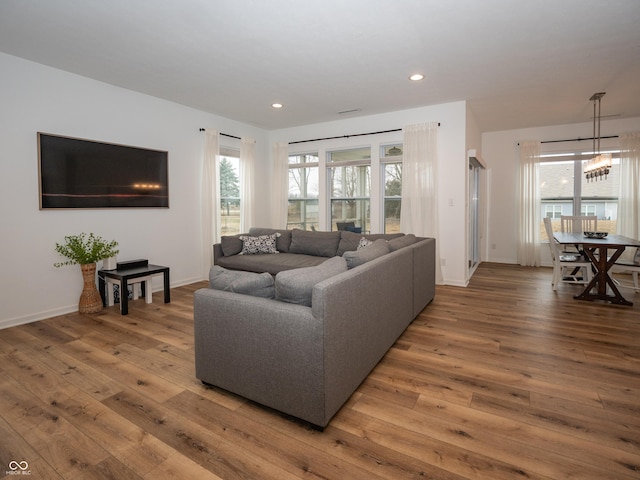 living area with baseboards, a healthy amount of sunlight, wood-type flooring, and recessed lighting