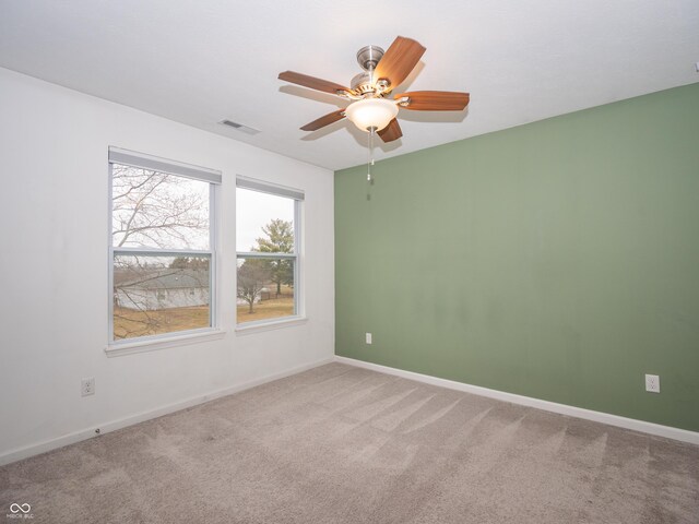 carpeted empty room with a ceiling fan, visible vents, and baseboards