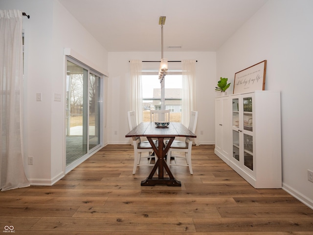 unfurnished dining area featuring visible vents, baseboards, and hardwood / wood-style floors