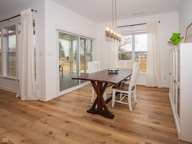 dining room featuring light wood finished floors, baseboards, visible vents, and a notable chandelier