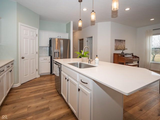 kitchen featuring decorative backsplash, appliances with stainless steel finishes, light wood-type flooring, white cabinetry, and a sink