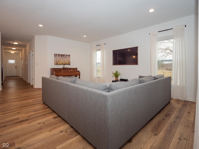 living area with baseboards, light wood-style flooring, and recessed lighting