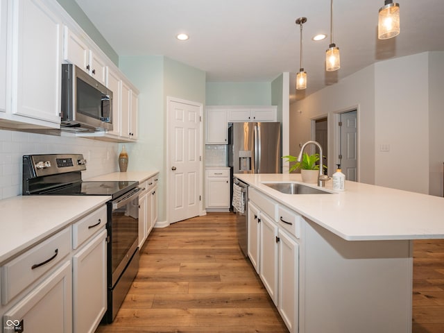 kitchen featuring stainless steel appliances, white cabinetry, a sink, and light wood-style flooring