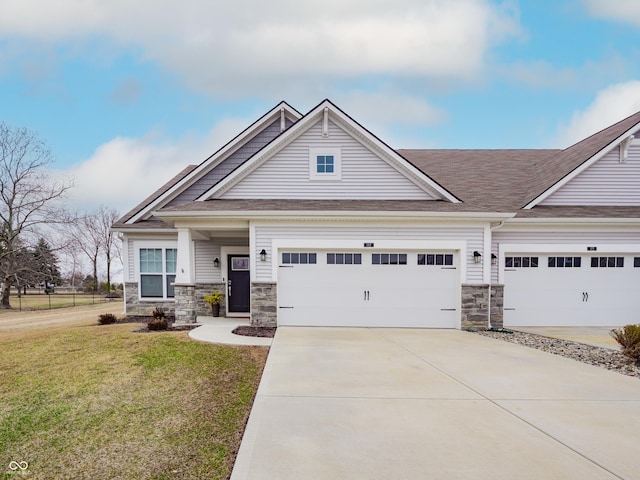 craftsman house with a front yard, stone siding, driveway, and an attached garage