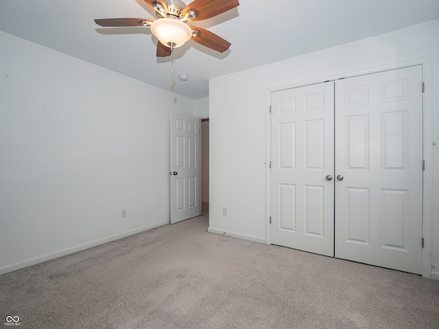 unfurnished bedroom featuring baseboards, a closet, a ceiling fan, and light colored carpet