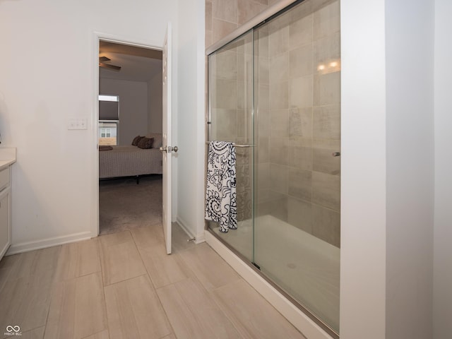 ensuite bathroom with a stall shower, connected bathroom, vanity, and baseboards