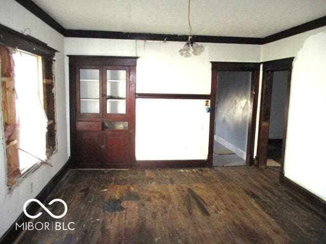 unfurnished dining area with ornamental molding and dark wood-type flooring